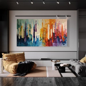 Puede incluir: Pintura abstracta de una ciudad con rayas verticales de colores en tonos de azul, morado, amarillo, naranja y rojo. La pintura se exhibe en una pared blanca en una sala de estar moderna.