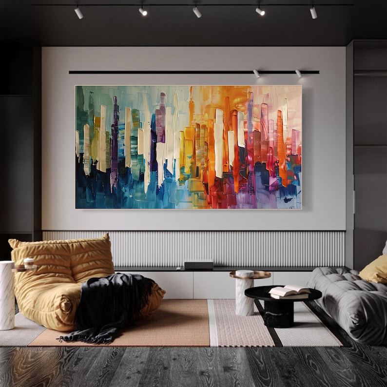 Puede incluir: Pintura abstracta de una ciudad con rayas verticales de colores en tonos de azul, morado, amarillo, naranja y rojo. La pintura se exhibe en una pared blanca en una sala de estar moderna.
