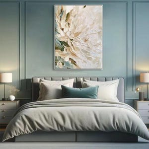 May include: A rectangular wall art piece featuring a thick, textured impasto oil painting of a large, abstract white and cream flower with subtle sage green accents, displayed in a thin white frame above a gray upholstered bed.