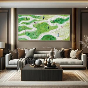 May include: Abstract painting of a golf course with green and white colors. The painting features multiple figures in various poses, suggesting a game of golf. The painting is framed and displayed on a wall in a living room setting.