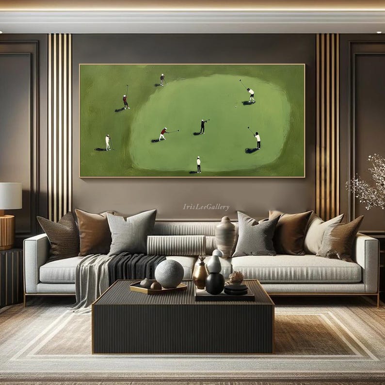 May include: A framed painting depicts a golf course scene with several golfers in action. The artwork features a green golf course with players in white and red attire. The painting is displayed above a modern sofa in a living room setting.