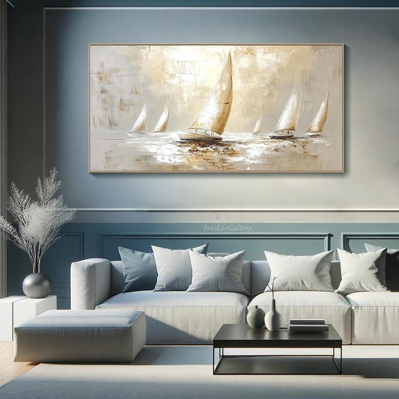 May include: An abstract painting of sailboats on the water in neutral tones. The artwork features several sailboats with white sails and a golden-beige background. The painting is framed in a gold-coloured frame and hangs above a grey sofa.