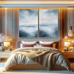 May include: A bedroom with a large bed with a beige duvet and a brown throw blanket. Two abstract paintings in blue and white tones hang above the bed on a wooden wall.