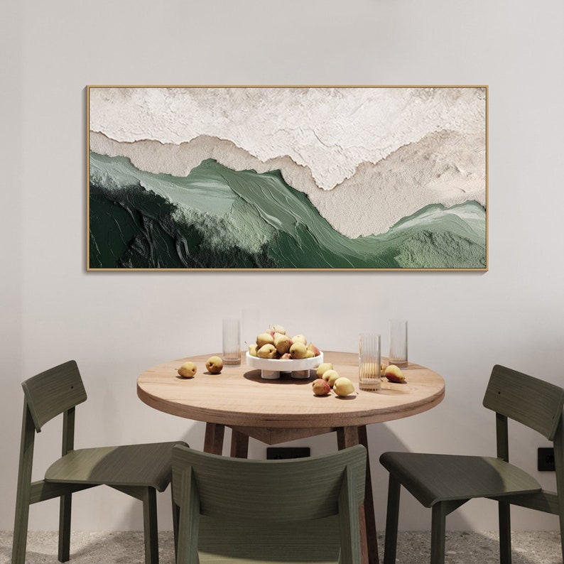 May include: A framed abstract painting with a green and white color scheme. The painting depicts a landscape with rolling hills and valleys. The painting is hanging on a white wall above a wooden table with four chairs.