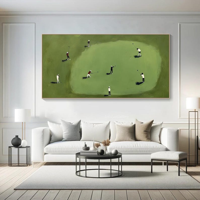 May include: An abstract golf-themed painting featuring golfers on a green course. The artwork depicts several figures in white, black, and red attire, engaged in the sport. The painting is framed in gold and hangs above a white sofa.
