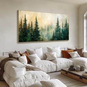 Puede incluir: Una pintura que representa una escena de bosque con altos pinos verdes en primer plano y un fondo brumoso y brumoso. La pintura est&aacute; enmarcada en un marco fino de oro y cuelga de una pared blanca sobre un sof&aacute; seccional blanco.