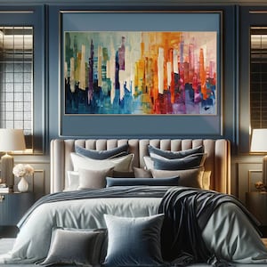 Puede incluir: Pintura abstracta de un horizonte urbano con rayas verticales de colores en tonos de azul, morado, amarillo, naranja y rojo. La pintura est&aacute; enmarcada y colgada en una pared sobre una cama con ropa de cama azul y blanca.