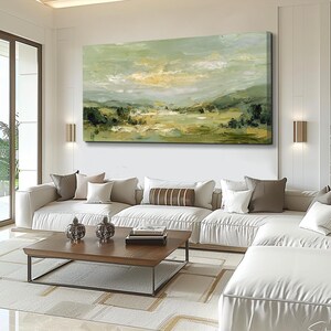 May include: An abstract landscape painting in shades of green, yellow, and white hangs above a white sectional sofa. The artwork depicts a serene scene of rolling hills and a cloudy sky. A wooden coffee table and decorative items complete the living room setting.