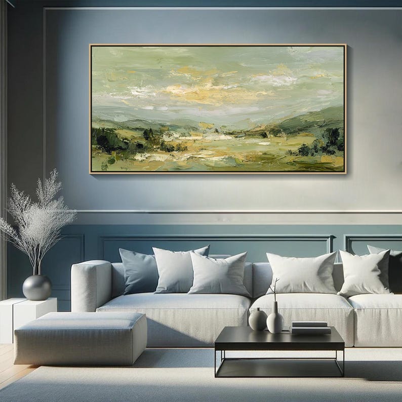 May include: An abstract landscape painting in a gold frame. The artwork features a serene scene with rolling hills, trees, and a cloudy sky. The color palette includes shades of green, yellow, and white, creating a calming and natural aesthetic.