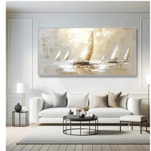 May include: An abstract oil painting of sailboats on water. The artwork uses a neutral palette of white, beige, and gold, with textured brushstrokes. The sailboats have white sails, and the water reflects the light. The painting is framed in a white rectangular frame.