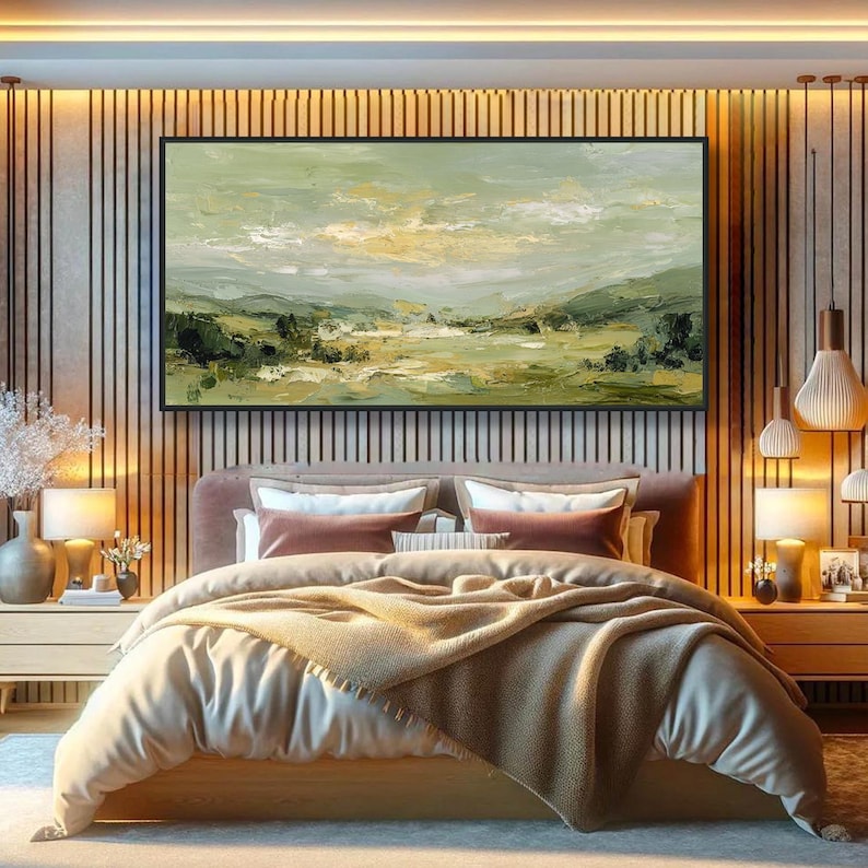 May include: A bedroom scene featuring a large landscape painting above a bed. The painting has a black frame and depicts a green and yellow landscape. The bed has a pink headboard, white bedding, and a tan blanket. Two nightstands with lamps flank the bed.