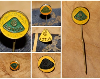May include: A collection of four vintage Lotus car logo pins. The pins are round and feature a green and yellow color scheme. The Lotus logo is a green triangle with the letters "Lotus" written in gold.