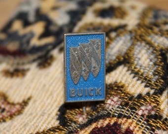 May include: A blue and silver pin with the Buick logo and the word "Buick" in white letters.