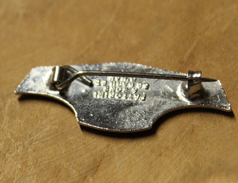 May include: Silver-toned metal pin with a bird design. The back of the pin has the text "BAYLORINI  BNDB 93  WYATT 93".