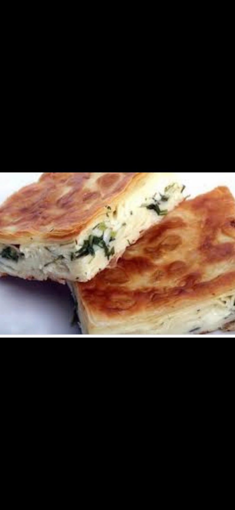 May include: Two golden brown pastries filled with a white cheese and green herbs. The pastries are layered and flaky.