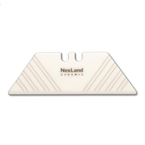 Può includere: Una lama per taglierino in ceramica bianca con la scritta "NexLand CERAMIC". La lama ha una forma trapezoidale con linee angolate e una parte superiore dentellata. La lama è progettata per il taglio di precisione.
