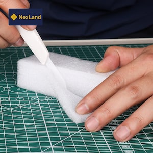 May include: A white craft knife cutting a white foam block on a green cutting mat. The knife is held by a person's hands. The logo "NexLand" is in the upper left corner.
