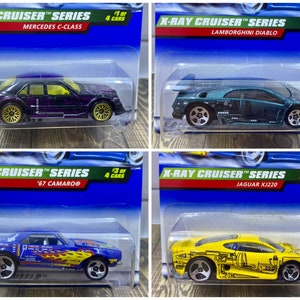 May include: Four toy car models from the X-Ray Cruiser series. The cars are a purple Mercedes C-Class, a teal Lamborghini Diablo, a blue '67 Camaro, and a yellow Jaguar XJ220. Each car has a clear plastic window showing the engine and chassis.