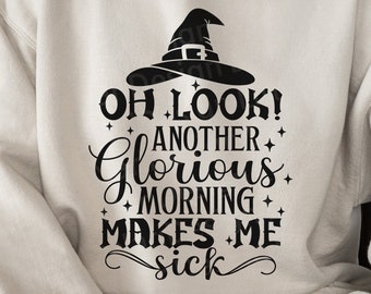 Op de afbeelding: Een witte hoodie met een zwarte heksenhoed en de tekst "OH LOOK! ANOTHER GLORIOUS MORNING MAKES ME SICK" gedrukt op de voorkant.