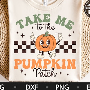 May include: A white t-shirt with the text "Take Me to the Pumpkin Patch" in a retro font. The text is in green, orange, and black. A cartoon pumpkin with a smiling face is in the center of the design.