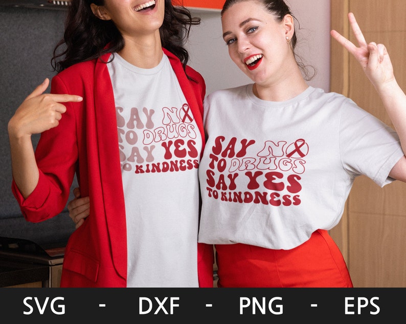 May include: Two women wearing white t-shirts with the text "Say No to Drugs Say Yes to Kindness" in red, retro-style lettering. The text is surrounded by a red ribbon.