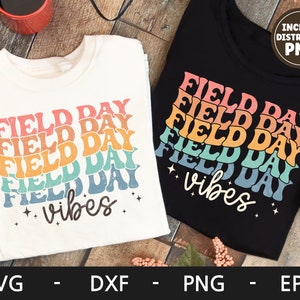 May include: Two white t-shirts with the text "FIELD DAY" repeated in a rainbow pattern and the words "vibes" in black. One shirt is on a black background and the other is on a wood background. The text "INCLUDE DISTRESSED PNG" is in a white box on the black shirt.