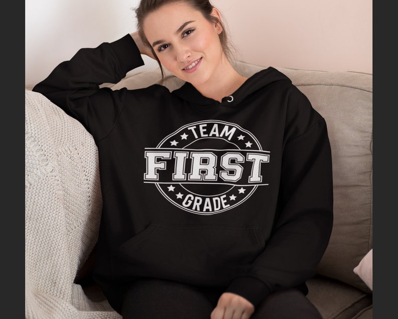 May include: Black hooded sweatshirt with a white circle graphic that says "Team First Grade" with stars around the circle.