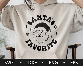 May include: A cream-coloured hoodie with a black graphic of Santa Claus's face and the text "SANTA'S FAVORITE" in a retro font.