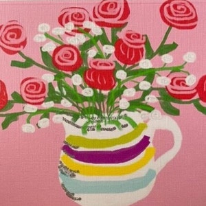 Può includere: Un'anfora a righe colorate piena di rose rosa e rosse e fiori bianchi. L'anfora ha un manico ed è su uno sfondo rosa.