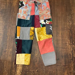Pu&ograve; includere: Pantaloni patchwork con vita con coulisse. I pantaloni presentano una variet&agrave; di tessuti nei toni del rosso, blu, verde, giallo e grigio. Il design patchwork include motivi floreali e paisley.