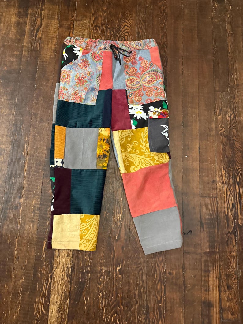 Pu&ograve; includere: Pantaloni patchwork con vita con coulisse. I pantaloni presentano una variet&agrave; di tessuti nei toni del rosso, blu, verde, giallo e grigio. Il design patchwork include motivi floreali e paisley.
