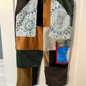 May include: Patchwork pants with a variety of colors and patterns, including brown, green, blue, and white. The pants have a drawstring waist and a patch pocket with the text "Grateful Dead" on it.