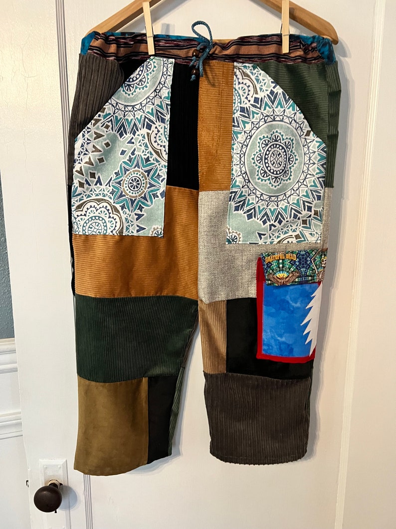 May include: Patchwork pants with a variety of colors and patterns, including brown, green, blue, and white. The pants have a drawstring waist and a patch pocket with the text "Grateful Dead" on it.