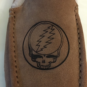 May include: Brown suede slippers with a black embroidered Grateful Dead logo.