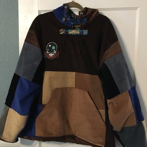 Pode incluir: Uma jaqueta de moletom marrom com capuz de veludo cotel&ecirc; com um design de patchwork. A jaqueta tem um grande bolso na frente e um capuz com cord&atilde;o. A jaqueta &eacute; decorada com um patch Grateful Dead e uma etiqueta "Grateful Dead".
