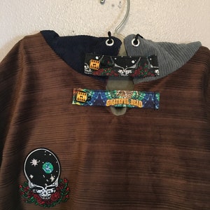 Pode incluir: Um moletom de veludo cotel&ecirc; marrom com um patch do Grateful Dead e um patch tie-dye. O moletom tem um capuz de veludo cotel&ecirc; azul marinho e cinza com um cord&atilde;o.