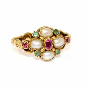 Può includere: Un anello d'oro con un gruppo di perle, rubini e smeraldi. L'anello ha una fascia ornata e una disposizione centrale di pietre preziose. Le perle sono bianche, i rubini sono rossi e gli smeraldi sono verdi.