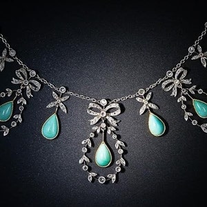May include: An elegant necklace with a delicate chain, bow and floral accents. The necklace features teardrop-shaped turquoise gemstones and sparkling clear stones, set against a dark background.