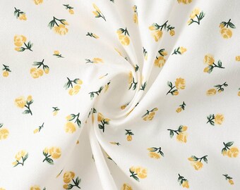 May include: White fabric with a repeating pattern of small yellow roses and green leaves. The floral design is scattered across the material, creating a delicate and feminine aesthetic. The fabric appears to be soft and lightweight.