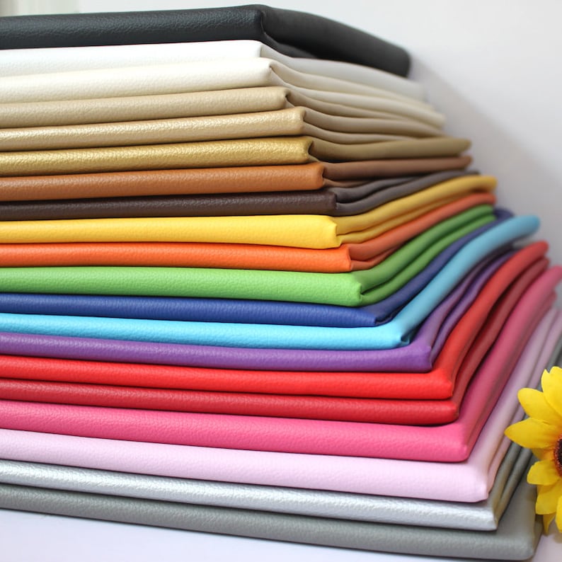 May include: A stack of 18 different colored faux leather fabric swatches. The colors include black, white, beige, gold, brown, yellow, orange, green, blue, purple, red, pink, light pink, gray, and silver.