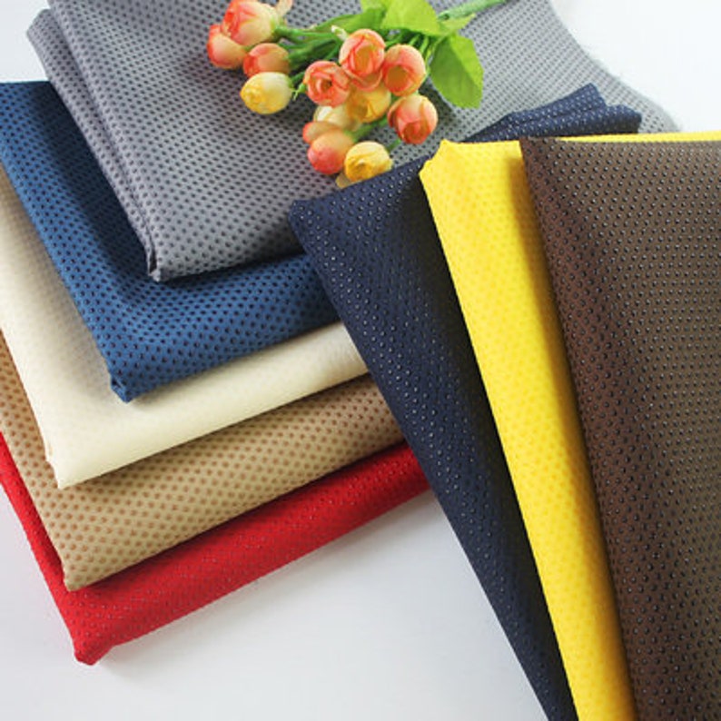 May include: A stack of eight different fabric swatches with a variety of colors and textures. The fabrics are all dotted with small holes.