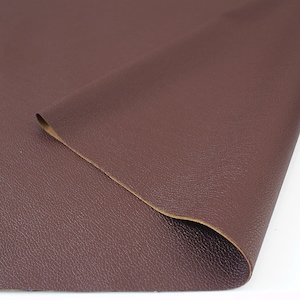 May include: A close-up of a piece of brown faux leather fabric with a textured surface.