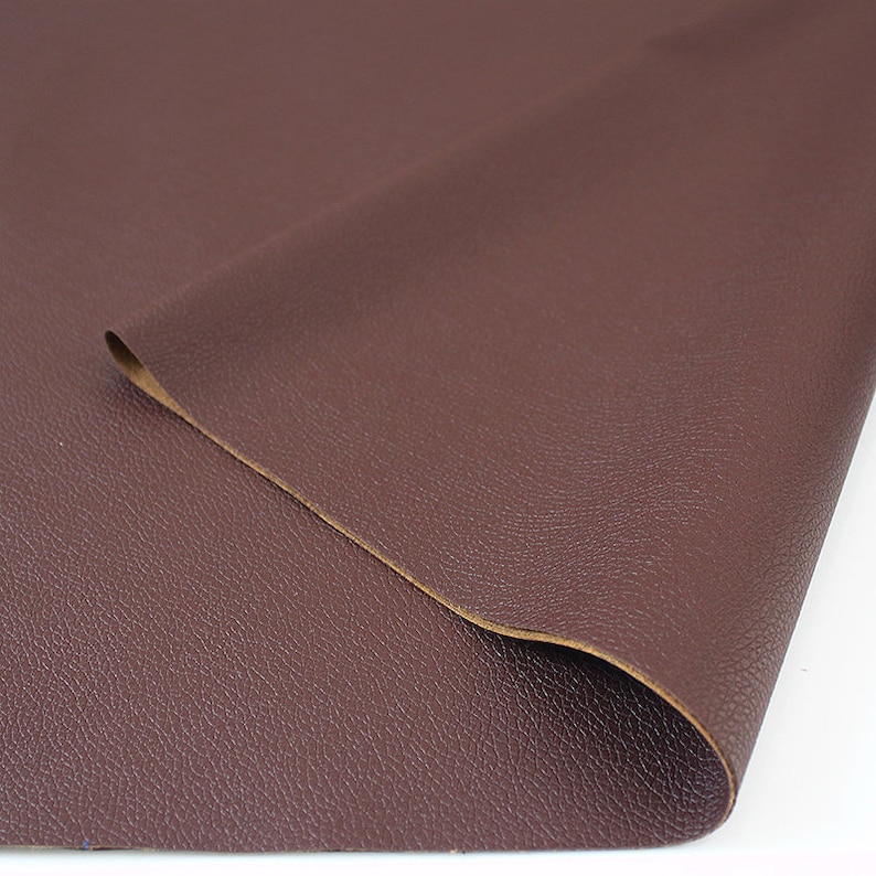 May include: A close-up of a piece of brown faux leather fabric with a textured surface.