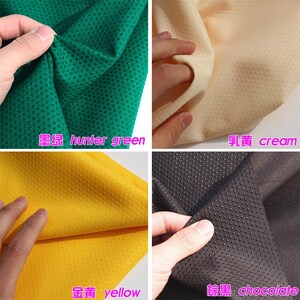 May include: Four fabric swatches with a textured, dotted surface. The swatches are hunter green, cream, yellow, and chocolate.