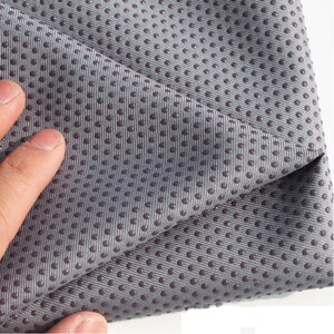 May include: Close-up of a gray yoga mat with a textured surface. The mat has small, raised dots that provide grip.
