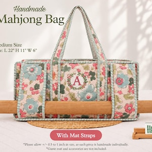 May include: A rectangular fabric Mahjong bag with a pink floral pattern, green striped trim, and a central letter A monogram. The bag features two top handles and horizontal straps holding a rolled bamboo mat. Text reads: Handmade Mahjong Bag, Medium Size, Size: L 22" H 11" W 6", With Mat Straps.