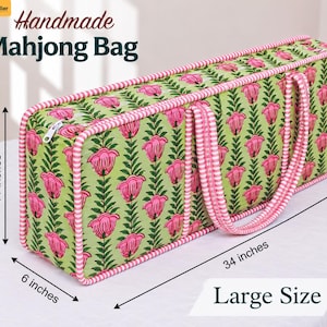 May include: A rectangular fabric Mahjong bag with a light green background and a repeating pink floral pattern. The bag features pink and white striped piping and handles. Dimensions are 28 cm high, 86 cm long, and 15 cm wide, labelled Large Size.