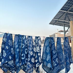 Peut inclure: Sept carrés de tissu bleus et blancs à motifs suspendus à une corde à linge. Les carrés de tissu présentent différents motifs, notamment des motifs floraux, géométriques et abstraits.