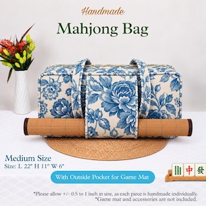 May include: A rectangular mahjong bag featuring a blue and white floral pattern with two fabric handles and an exterior pocket. The bag measures 22 inches long, 11 inches high, and 6 inches wide, and includes a rolled bamboo game mat.