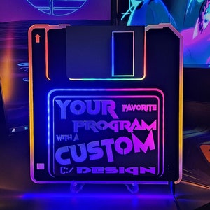 May include: A black and white 3.5 inch floppy disk shaped light with a rainbow LED glow. The light has the text "Your Favourite Program With A Custom Design" on the front.